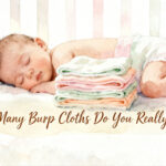stack of folded burp cloths next to a newborn